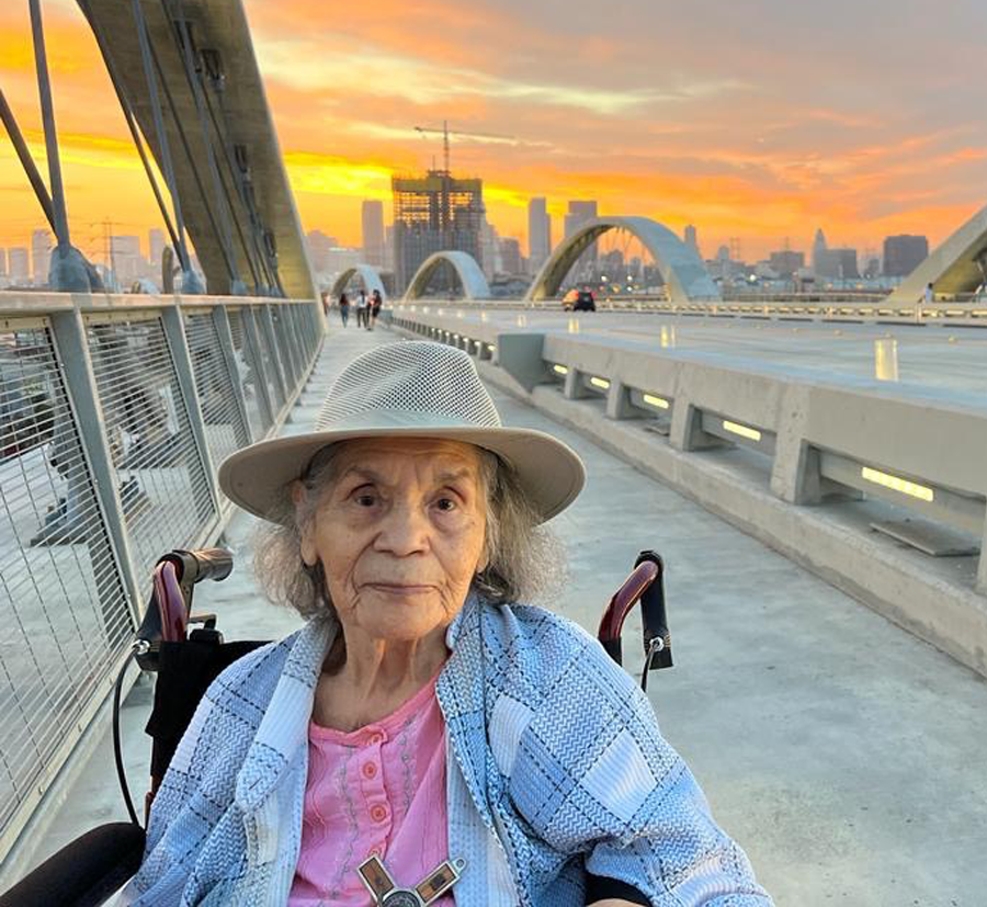 Juana Beatriz Gutiérrez on a bridge in Los Angelos with a sunset and the city skyline behind her.